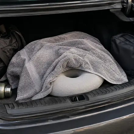A donut cushion hidden under a towel in a car trunk
